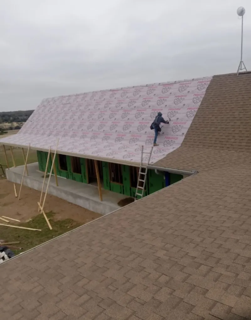 Worker preparing underlayment for a metal roof installation in Midway